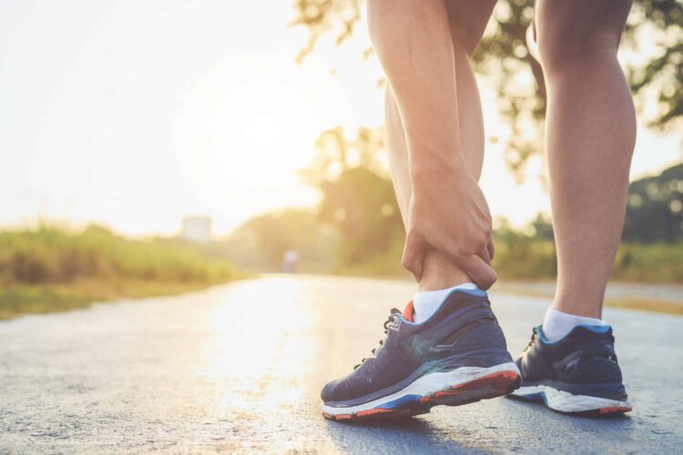 Runner grabbing ankle in pain after working out Runner grabbing ankle in pain after working out