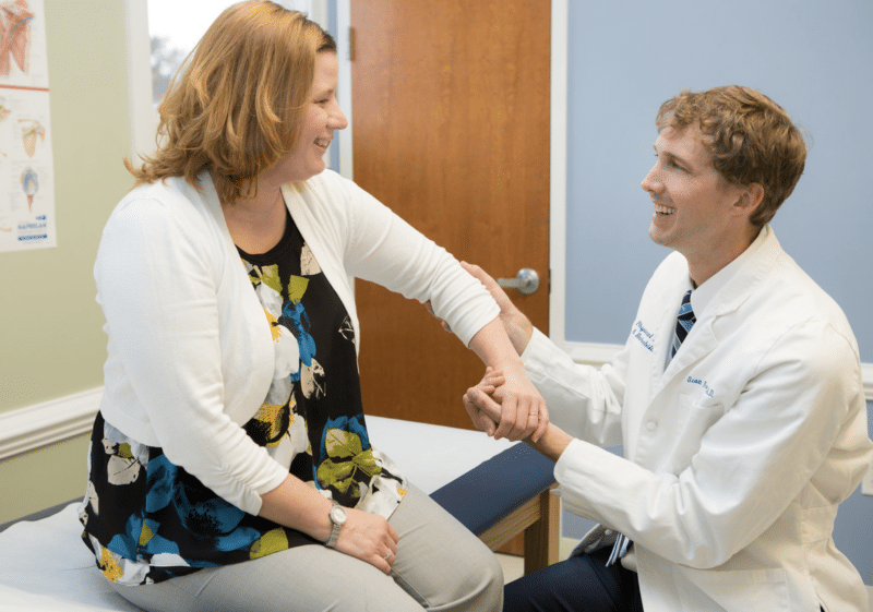 Doctor-helping-patient-elbow-pain-management