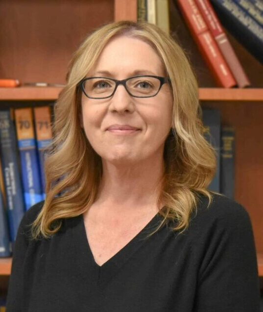 Headshot of wendy inside in front of bookshelf management team