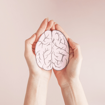 Understanding the connection between mental health and sports injuries 4 Hands holding an illustration of the human brain, representing the connection between mental health and sports injuries