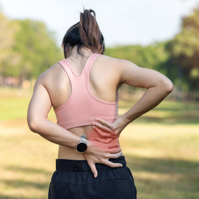 Tips for preventing sports-related back pain 2 Female athlete outside, holding lower back, experiencing back pain
