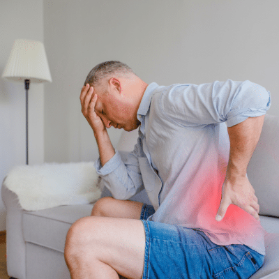 Chronic pain vs acute pain: understanding the difference 3 Older man sitting on a bed while holding his back in pain, representing chronic pain vs acute pain